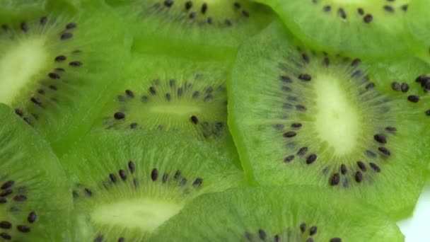 Fondo en forma de tiradas de kiwi en rodajas, fruta de kiwi verde jugosa o grosella china - Imágenes, Vídeo