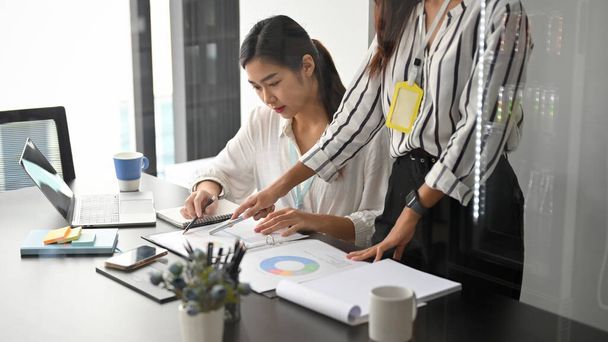 Junge asiatische Mitarbeiterinnen arbeiten mit weiblichen Führungskräften im Besprechungsraum an Papierkram. - Foto, Bild