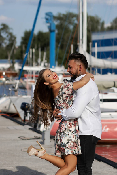 Vista lateral de pareja alegre en el amor abrazándose en el puerto con barcos en el día soleado en verano - Foto, imagen