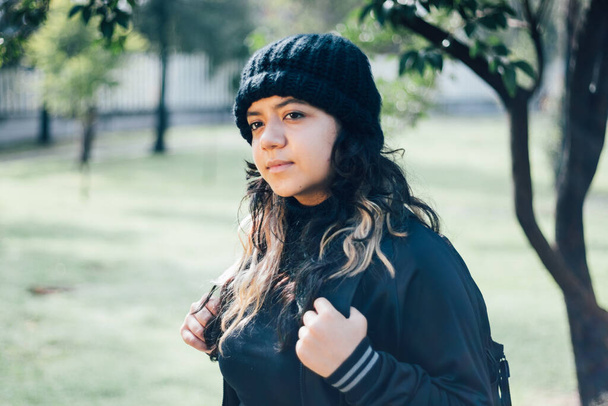 Contemplative latin teenager college girl walking at the park - Foto, imagen