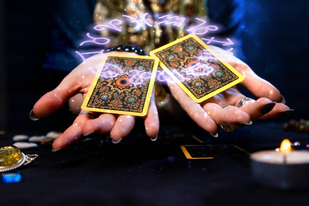 Χαρτογράφηση. Η μάντισσα έχει δύο κάρτες Ταρώ στις παλάμες της. Ο ζωδιακός κύκλος απεικονίζεται πάνω από το χέρι με τα φύλλα. Η έννοια της μαντείας, της αστρολογίας και του εσωτερισμού. - Φωτογραφία, εικόνα