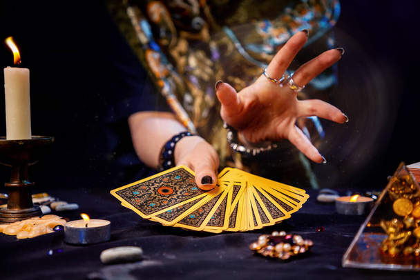 La adivina sostiene un fan de las cartas en sus manos y lanza un hechizo con su mano. Primer plano. El concepto de adivinación, magia y esoterismo. - Foto, imagen
