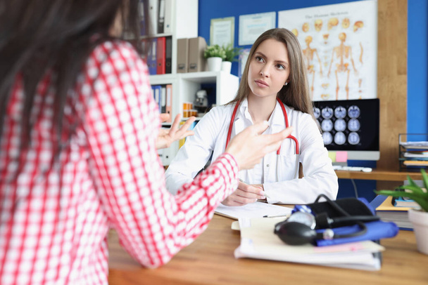 Portrait of serious female doctor listening carefully to patient. - Photo, Image