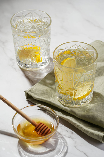 Dos vasos con agua y limón, miel en la luz de la mañana - desayuno - Foto, imagen