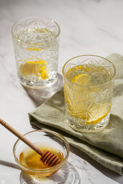 Дві склянки з водою і лимоном, мед в ранковому світлі - сніданок
 - Фото, зображення