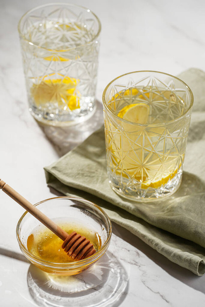 Two glasses with water and lemon, honey in the morning light - breakfast - Fotoğraf, Görsel