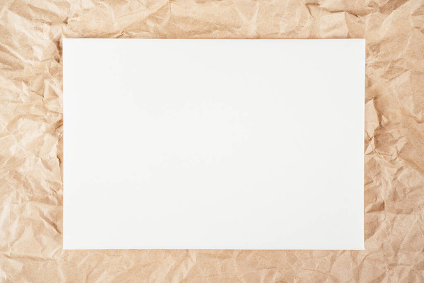 Фон изображения грубой смятой переработанной текстурированной крафтовой бумаги с белым картонным полотном посередине. Вид сверху. Копирование пространства - Фото, изображение