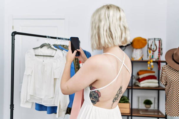 Молодая белая женщина делает фото одежды в магазине одежды - Фото, изображение
