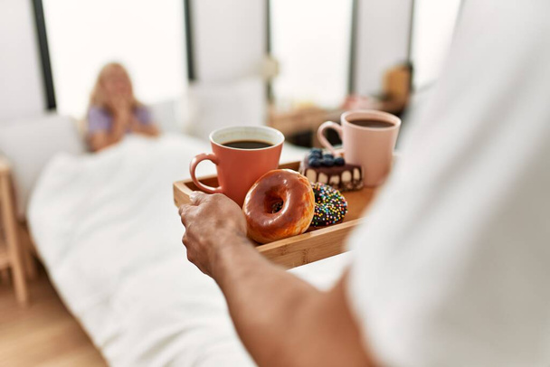 Man surprising his girlfriend with breakfast on the bed at home. - Photo, Image