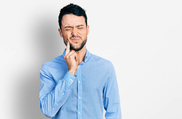 歯痛や歯の病気のために痛みを伴う式で手で口に触れるカジュアルなビジネスシャツを着てひげを持つヒスパニック系の男。歯科医  - 写真・画像