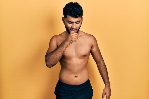 Arab man with beard wearing swimwear shirtless feeling unwell and coughing as symptom for cold or bronchitis. health care concept.  - Photo, Image