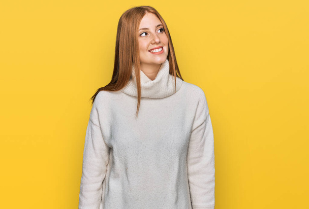 Молодая ирландская женщина в обычном зимнем свитере смотрит в сторону с улыбкой на лице, естественным выражением лица. смеясь уверенно.  - Фото, изображение