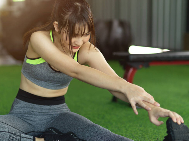 Attraktive junge, fitte Frau kühlt sich nach dem Training ab, trainiert Dehnen ihres Beines im Fitnessstudio. - Foto, Bild