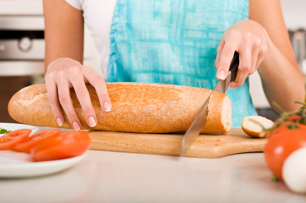Woman cutting bread on the kitchen (shallow DOF) - Foto, Imagen