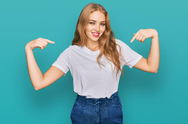Young caucasian girl wearing casual white t shirt looking confident with smile on face, pointing oneself with fingers proud and happy.  - Photo, Image