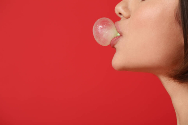 Young woman with chewing gum on color background, closeup - 写真・画像