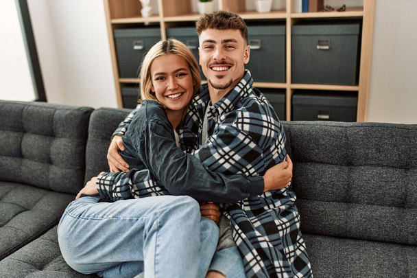 Young caucasian couple smiling happy and hugging sitting on the sofa at home. - Valokuva, kuva
