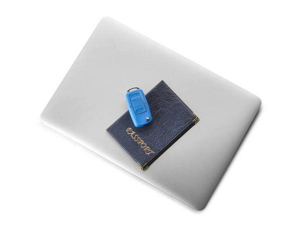 Laptop, útlevél és kulcstartó fehér háttérrel. Autóbérlés koncepciója - Fotó, kép