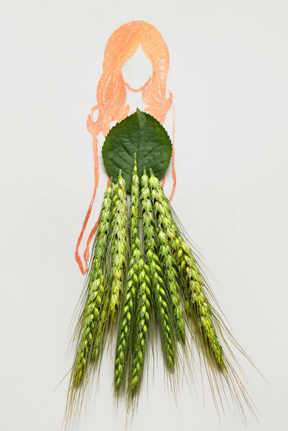 Mujer dibujada en vestido hecho de espiguillas de trigo sobre fondo claro - Foto, imagen