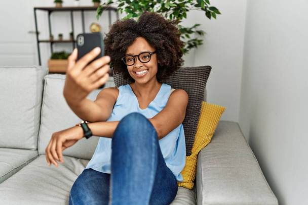 Νεαρή Αφροαμερικανή γυναίκα χαμογελώντας αυτοπεποίθηση κάνει selfie από το smartphone στο σπίτι - Φωτογραφία, εικόνα