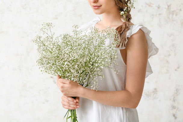 mooie jonge vrouw met boeket van bloemen op lichte achtergrond - Foto, afbeelding