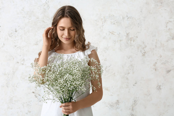 Pretty young woman with bouquet of flowers on light background - Photo, Image