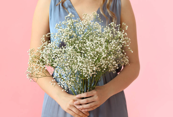 Hübsche junge Frau mit Blumenstrauß auf farbigem Hintergrund - Foto, Bild
