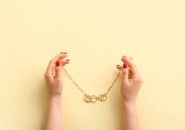 Woman with beautiful manicure holding necklace on color background - Photo, Image