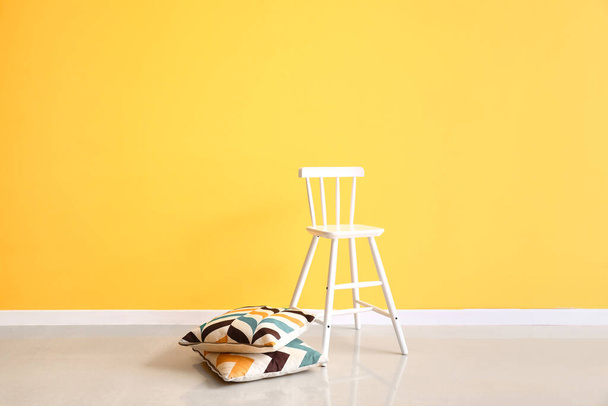 Renkli duvarın yanında modern sandalye ve yastıklar - Fotoğraf, Görsel