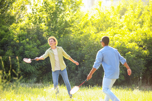 Молоді чоловіки грають у бадмінтон на відкритому повітрі
 - Фото, зображення