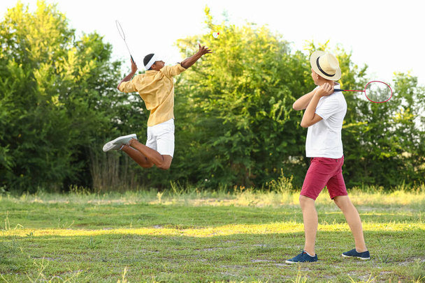 Молоді чоловіки грають у бадмінтон на відкритому повітрі
 - Фото, зображення