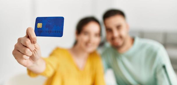 Jeune couple hispanique tenant une carte de crédit à la maison. - Photo, image
