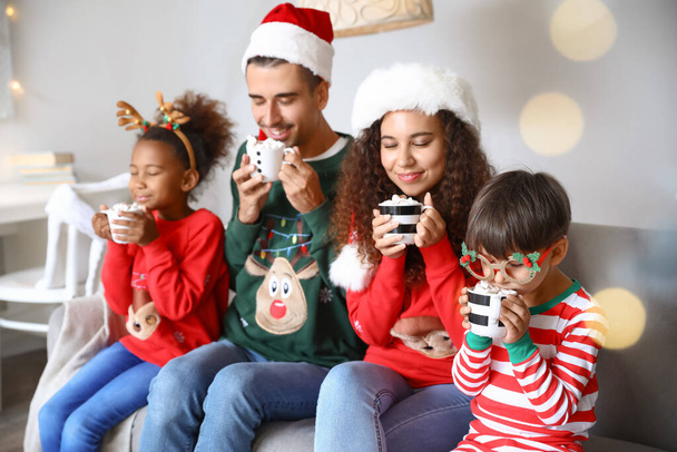 Счастливая семья с детьми, пьющими горячее какао дома в канун Рождества - Фото, изображение