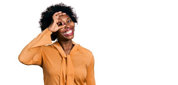afro americano donna con afro capelli indossare elegante camicia sorridente felice fare ok segno con mano sugli occhi guardando attraverso le dita  - Foto, immagini