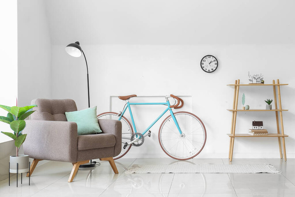 Interieur van lichte woonkamer met fauteuil, plank en fiets - Foto, afbeelding