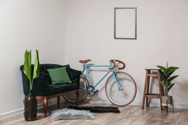 Interior of light living room with green sofa and bicycle - Фото, изображение