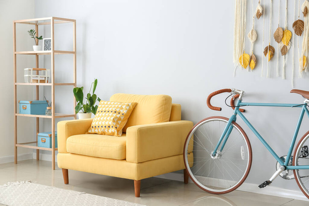 Interior de salón luminoso con sillón amarillo y bicicleta - Foto, Imagen