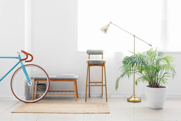 Interior of light room with chair, ottoman, lamp and bicycle - Фото, изображение