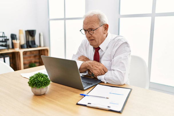 Senior muž pracující v kanceláři pomocí počítače notebook vypadá ospalý a unavený, vyčerpaný pro únavu a kocovinu, líné oči ráno.  - Fotografie, Obrázek