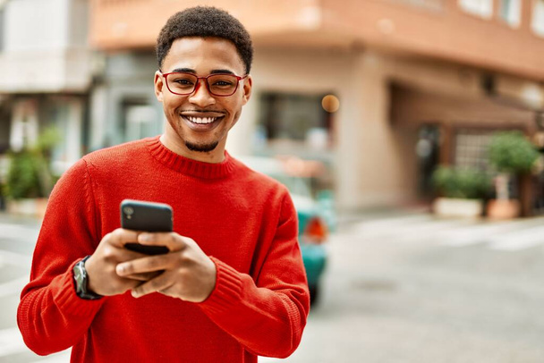 Schöner afrikanisch-amerikanischer Mann im Freien mit dem Smartphone eine Nachricht tippen - Foto, Bild