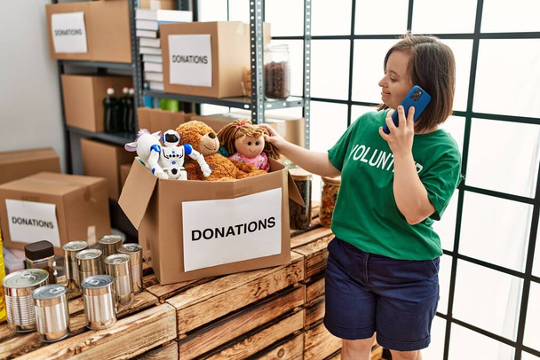 Brunette woman with down syndrome standing box speaking on the phone at donations stand - Photo, Image
