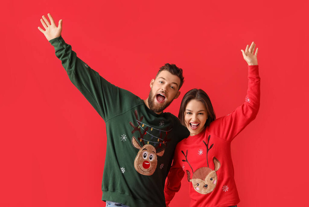 Happy young couple in stylish Christmas clothes on color background - Photo, Image