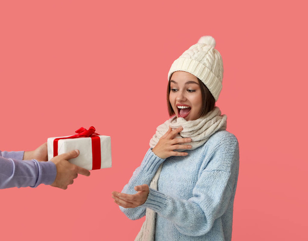 Молодая женщина получает рождественский подарок от своего парня на цветном фоне - Фото, изображение