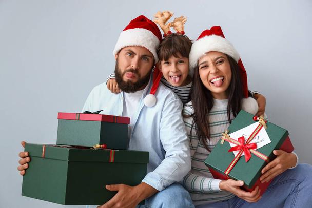 Gelukkige ouders met hun kleine zoon en kerstcadeaus op lichte achtergrond - Foto, afbeelding