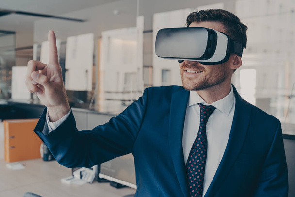 Молодий фінансист носить окуляри для гарнітури VR, стоячи у своєму офісі
 - Фото, зображення