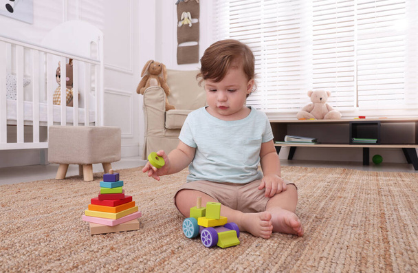 Cute little boy playing with toys on floor indoors - Foto, Bild