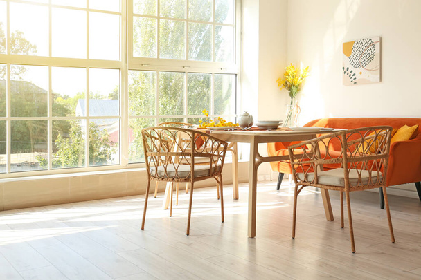 Wnętrze jasnej jadalni z wiklinowymi krzesłami - Zdjęcie, obraz