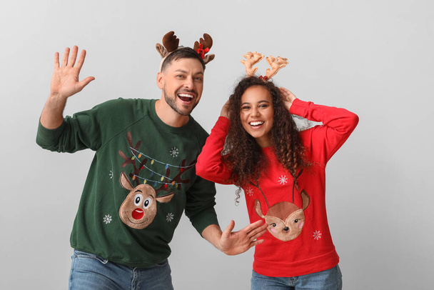 Pareja feliz en suéteres de Navidad sobre fondo claro - Foto, Imagen