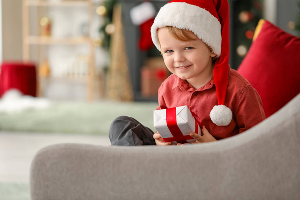 Little boy in Santa hat and with gift at home on Christmas eve - Фото, зображення