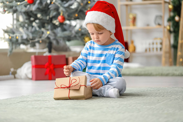 Little boy in Santa hat and with gift at home on Christmas eve - Foto, immagini